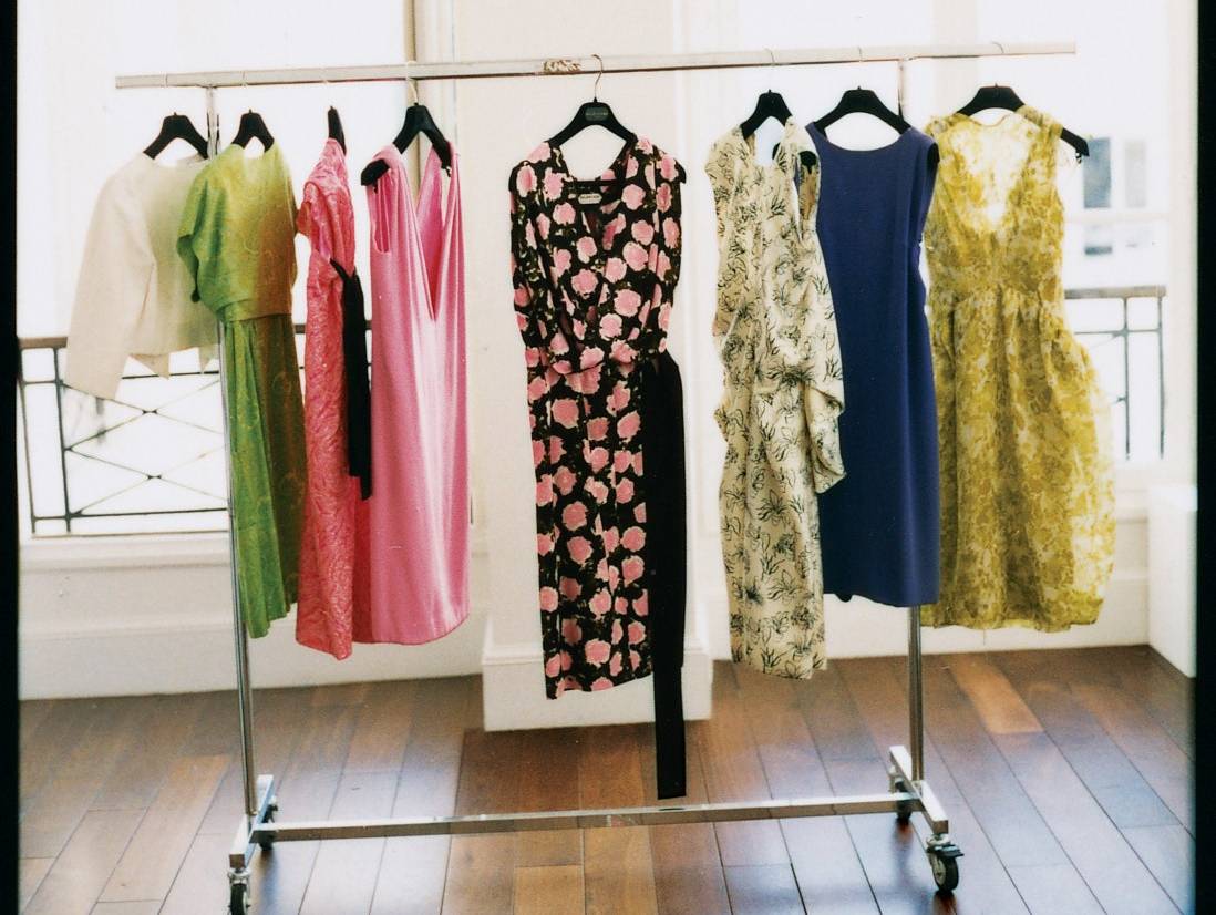 A rack of brightly colored clothes sitting in front of a window