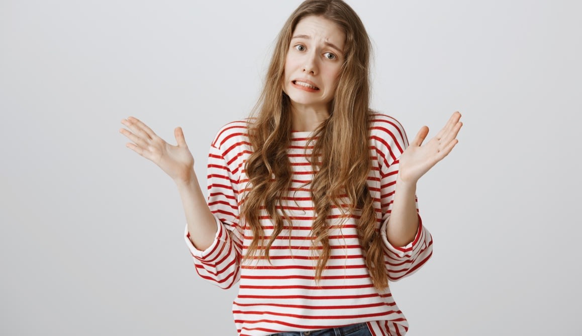 A woman holding her hands up, shrugging her shoulders, and making a face as if to say "I don't know".