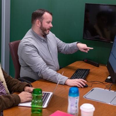 Ryan Harris, Head of Research and Instructional services points at computer screen while helping a student.