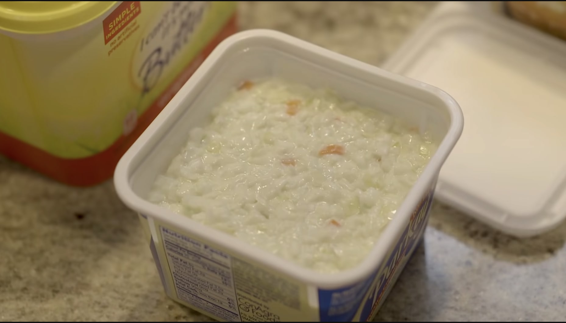 A small plastic butter tub of leftover coleslaw