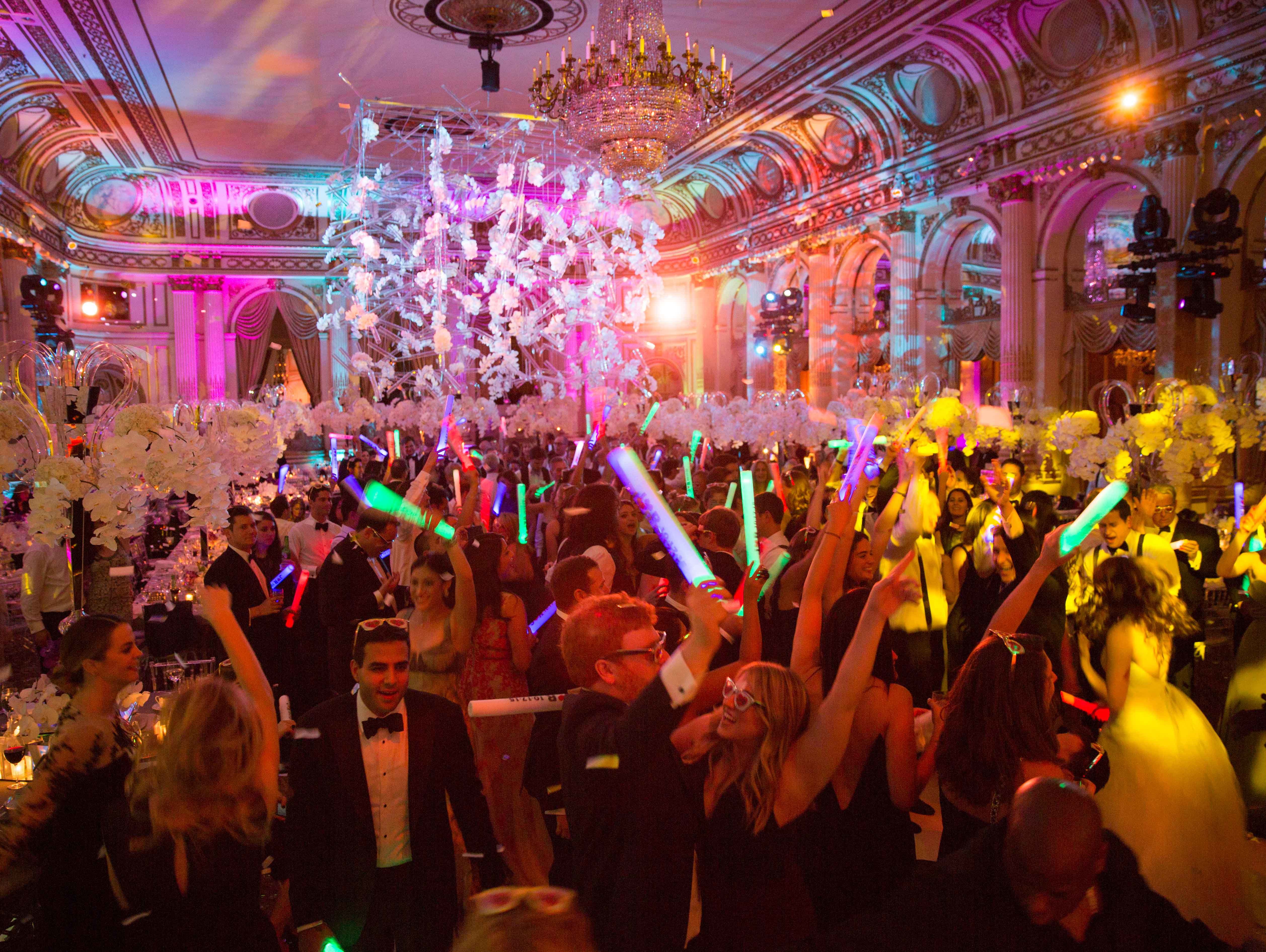 Wedding reception party with lots of people on the dance floor waving glow sticks 