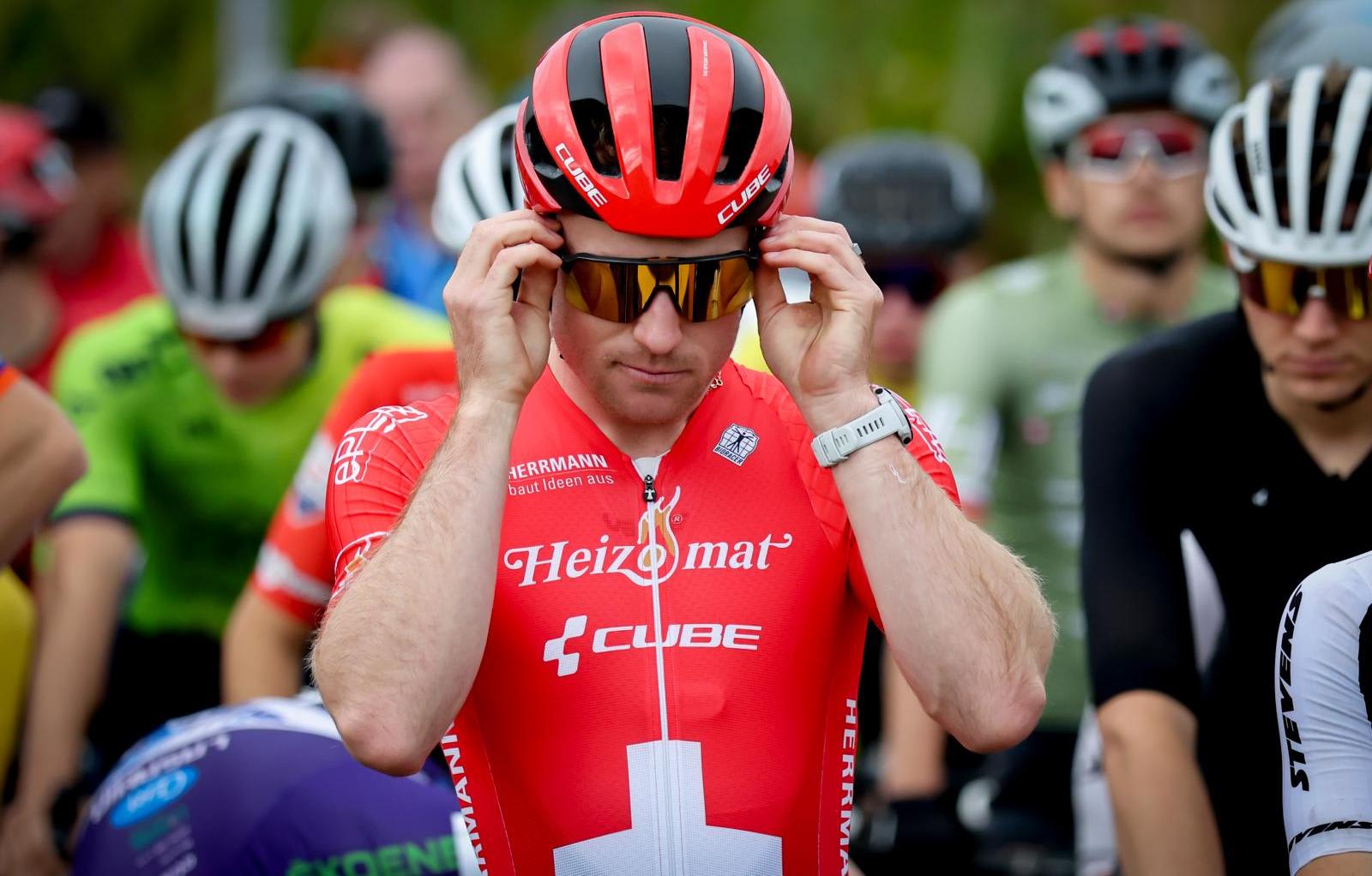 Ein stehender Rennvelofahrer richtet seine Sonnenbrille