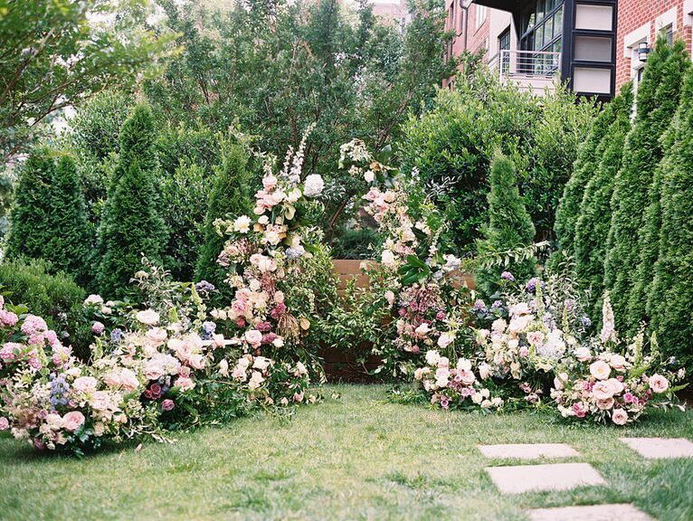 an elaborate pink floral installation decorates a garden wedding venue