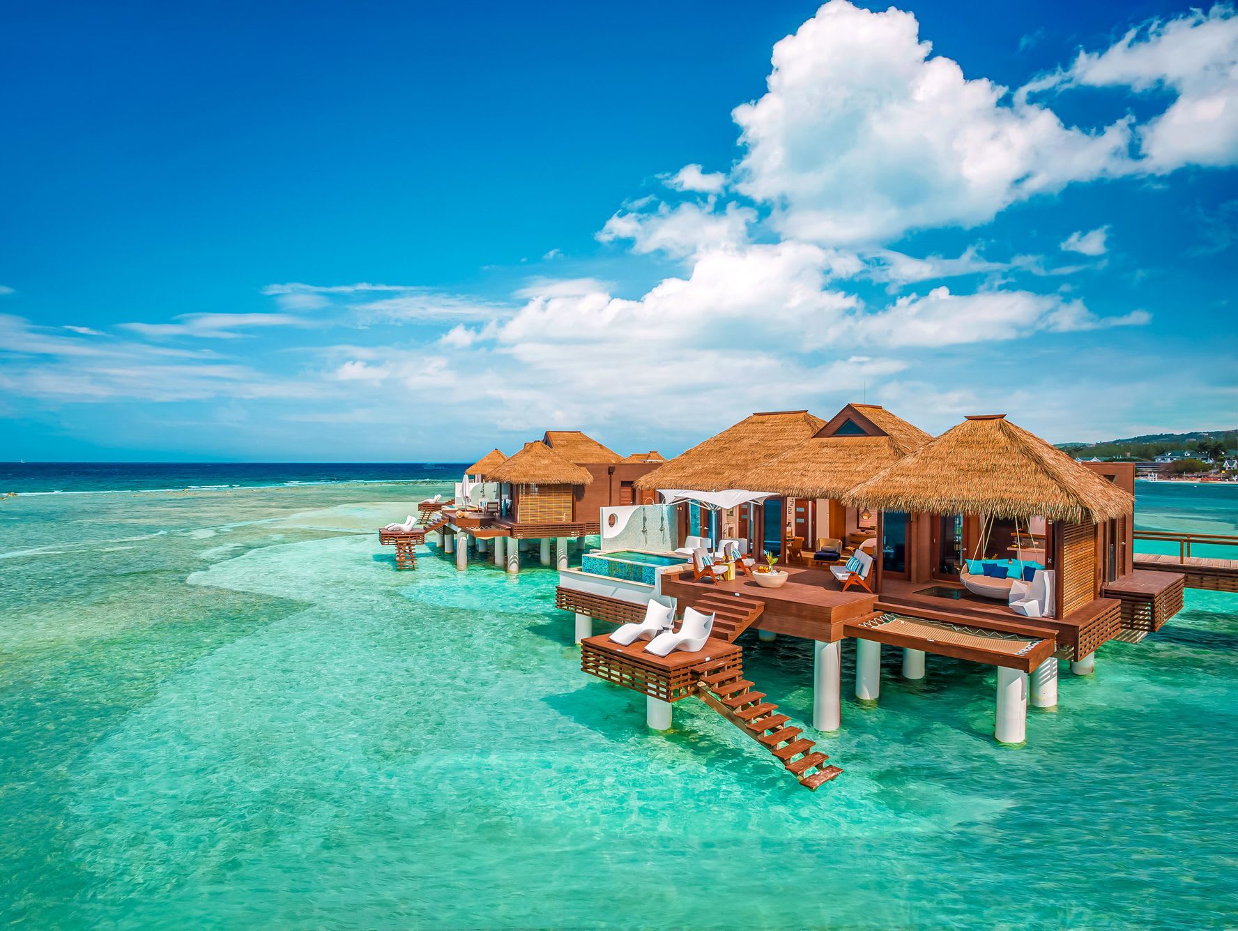 island cabins sit overtop of a vibrant blue ocean