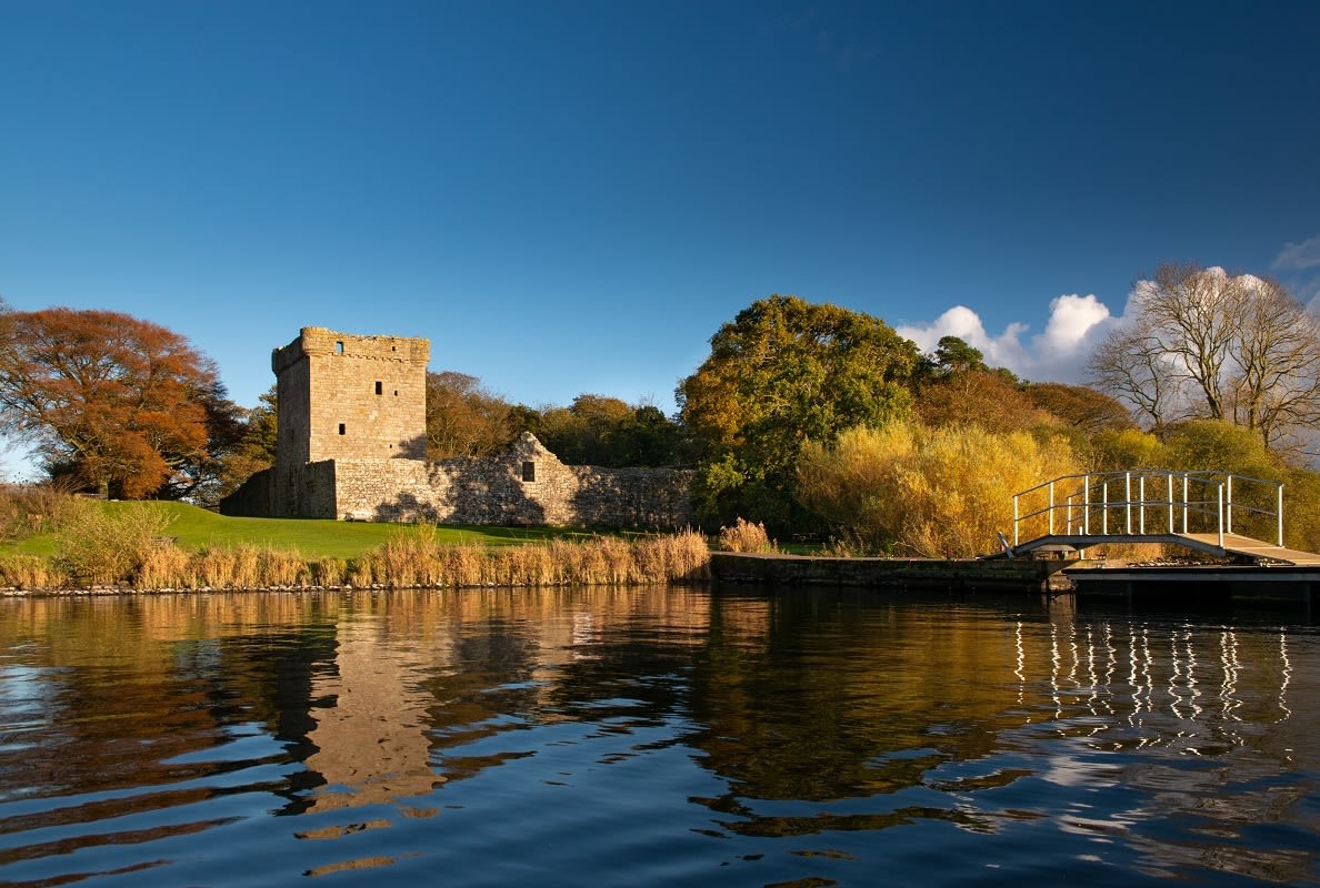 Calm water lapping at the shores of a small island, on which there is a ruined castle