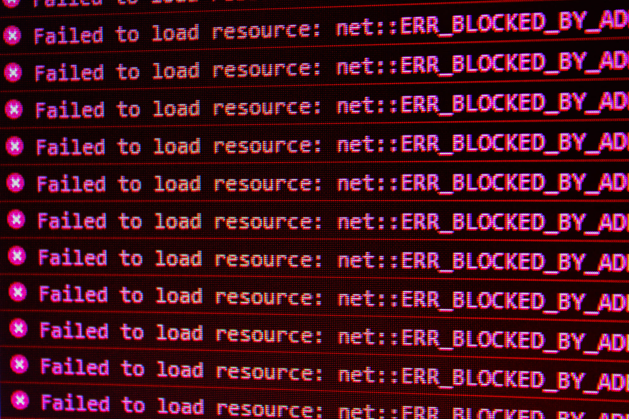 A computer screen with the repeated text in pink: "Failed to load resource: net::ERR_BLOCKED_BY_AD' repeatedly down the page