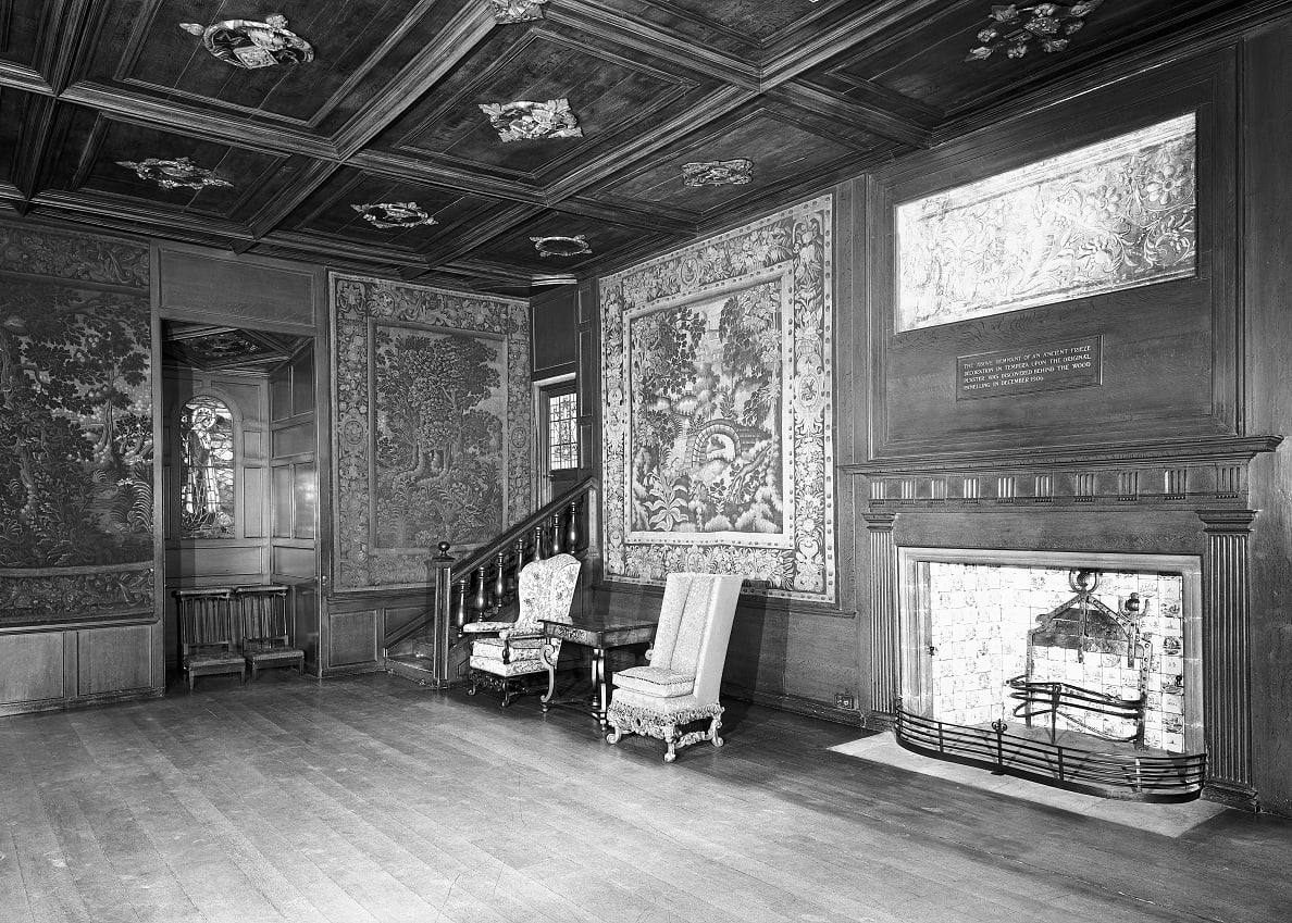 A black and white arhcive photo of a royal chamber within a palace. Two armchairs are placed beside an ornate fireplace.