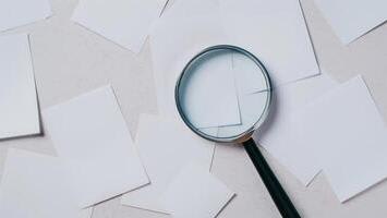 magnifying-glass-over-a-pile-of-white-paper-documents-photo