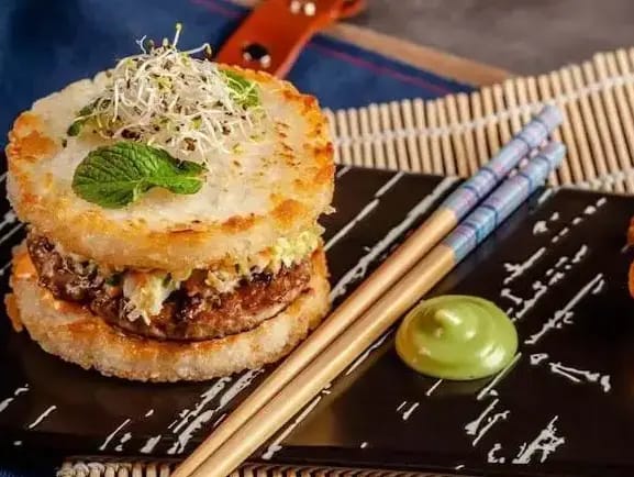 A-fusion-style-burger-with-a-crispy-rice-bun-served-on-a-plate-with-chopsticks