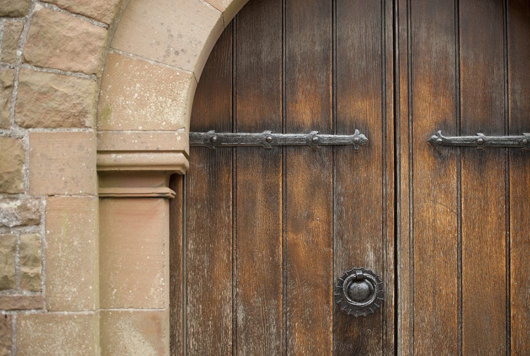 Large wooden doors at the entrance to a castle with a large metal door knocker