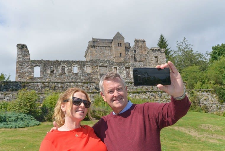 Man and woman posing to take a selfie in front of a castle.