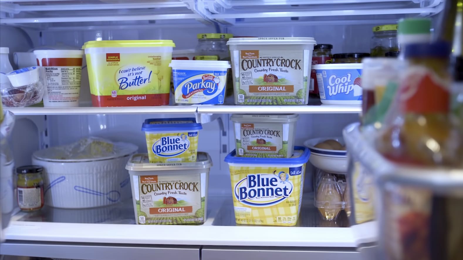 An open fridge filled with several different butter tubs
