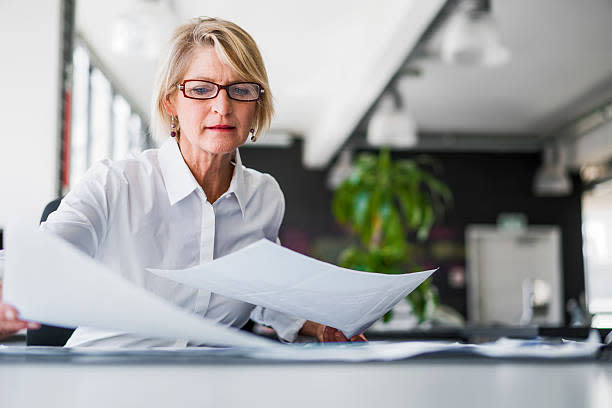 businesswoman-examining-documents-at-desk