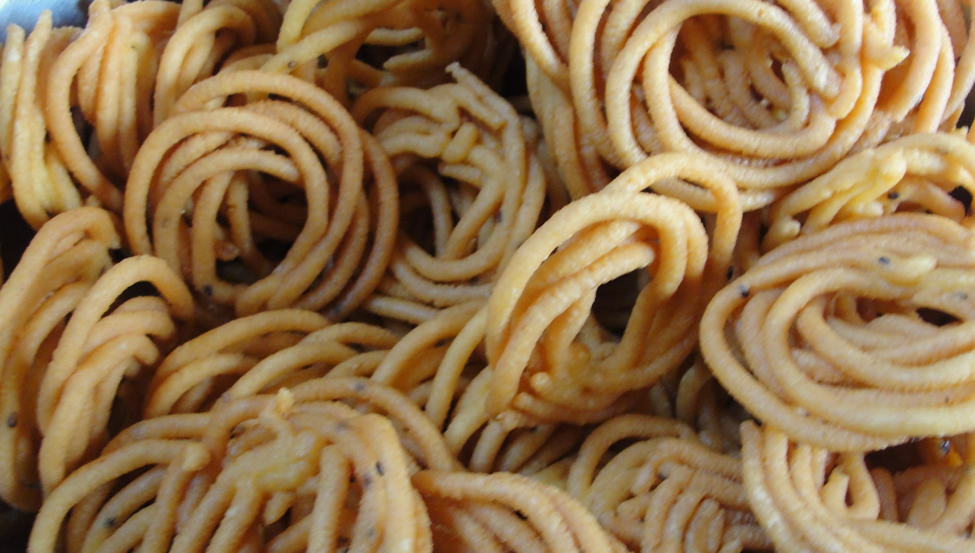 A pile of lightly fried, smooth and coiled murukku
