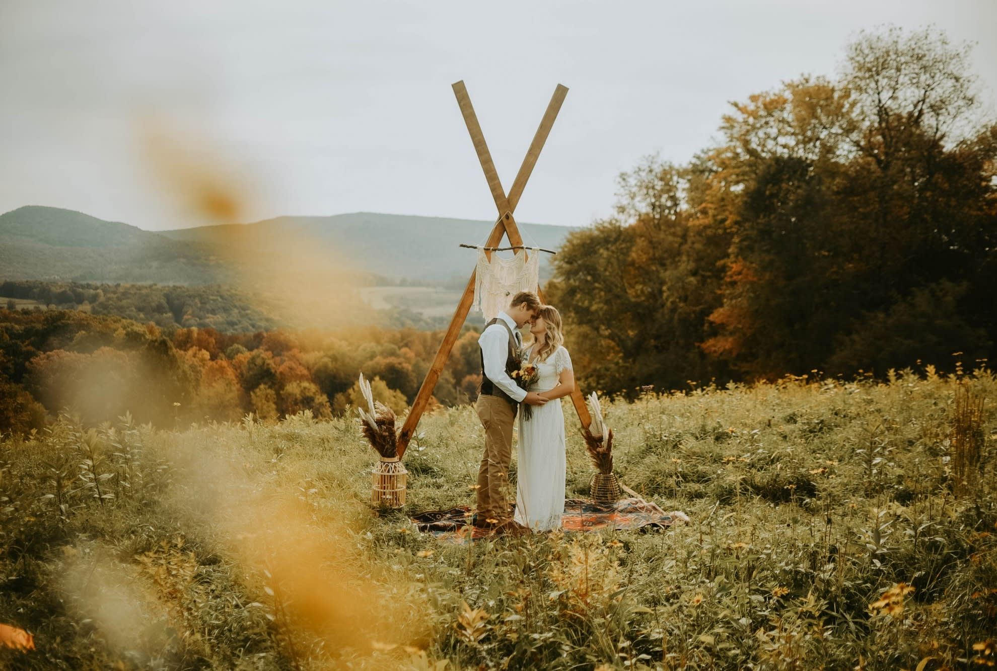 couple standing in field holding hands and looking into eachothers eyes while reciting vows during elopement ceremony. Field overlooks Sugarloaf Mountain and Ohiopyle State Park.