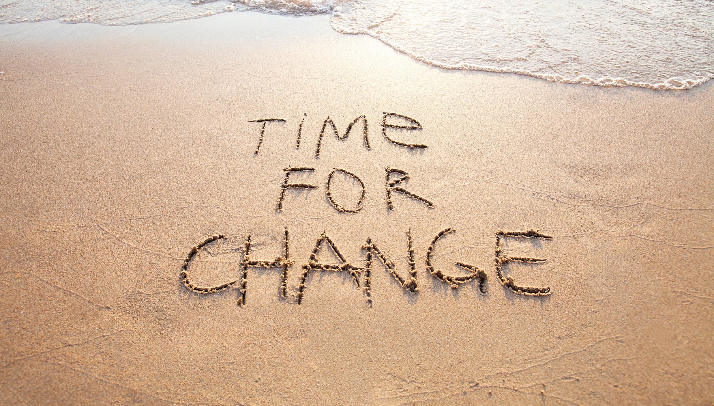 The sand by the sea with a writing on it that says "Time for change"