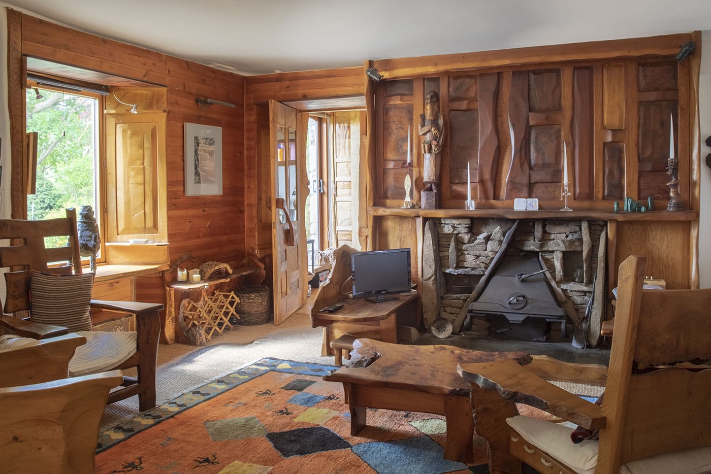 A living room filled with carved wooden furniture. The walls are covered with wooden panels, and decorative carved wood features