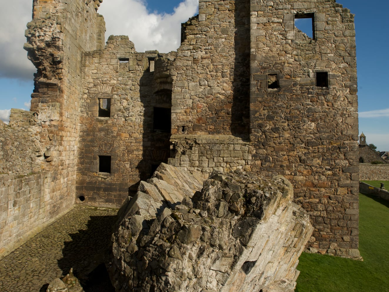 Ruins of Aberdour Castle with a large chunk of fallen down wall on the ground.