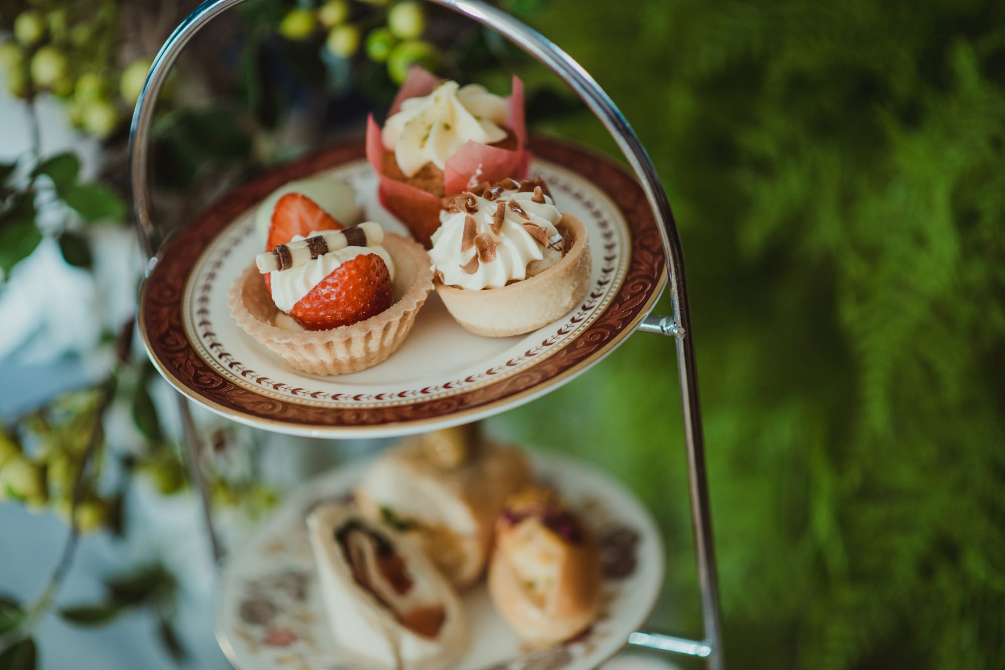 A cake stand with cakes and sandwiches on it