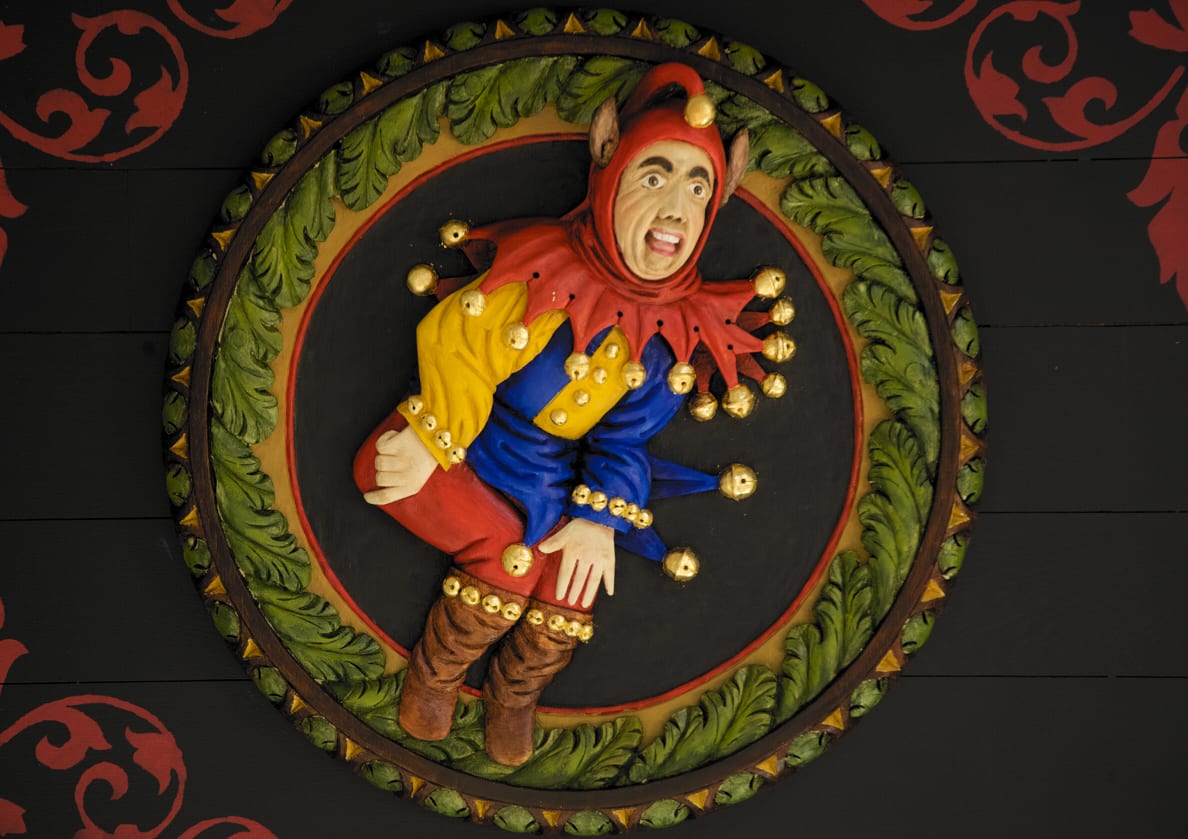 A colourful wooden carving of a court jester in a multicoloured outfit