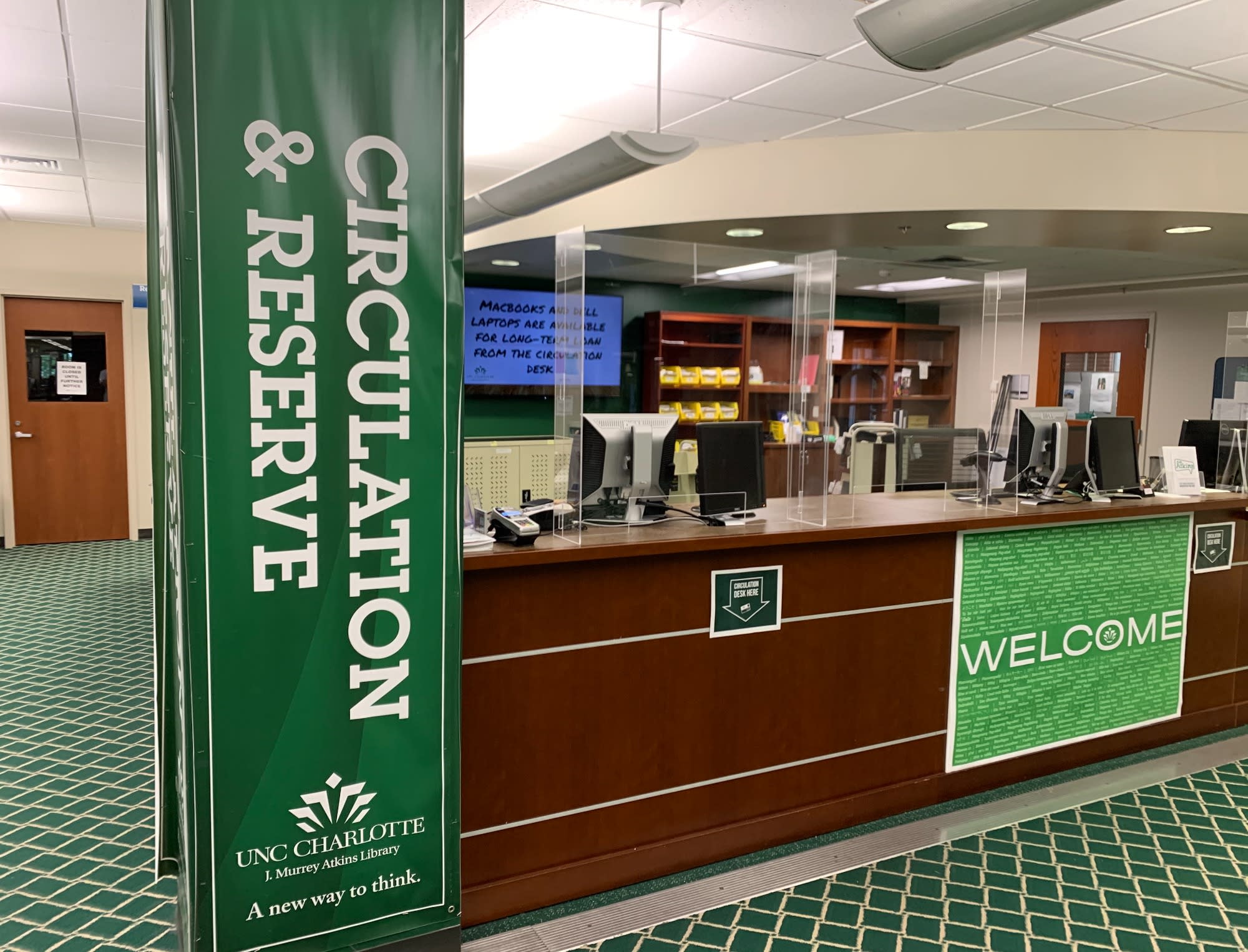 Picture of Atkins Library circulation and research help desk with plastic shields.  