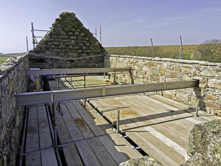 Interior of roofless ruined building with two steel I-beams in place.