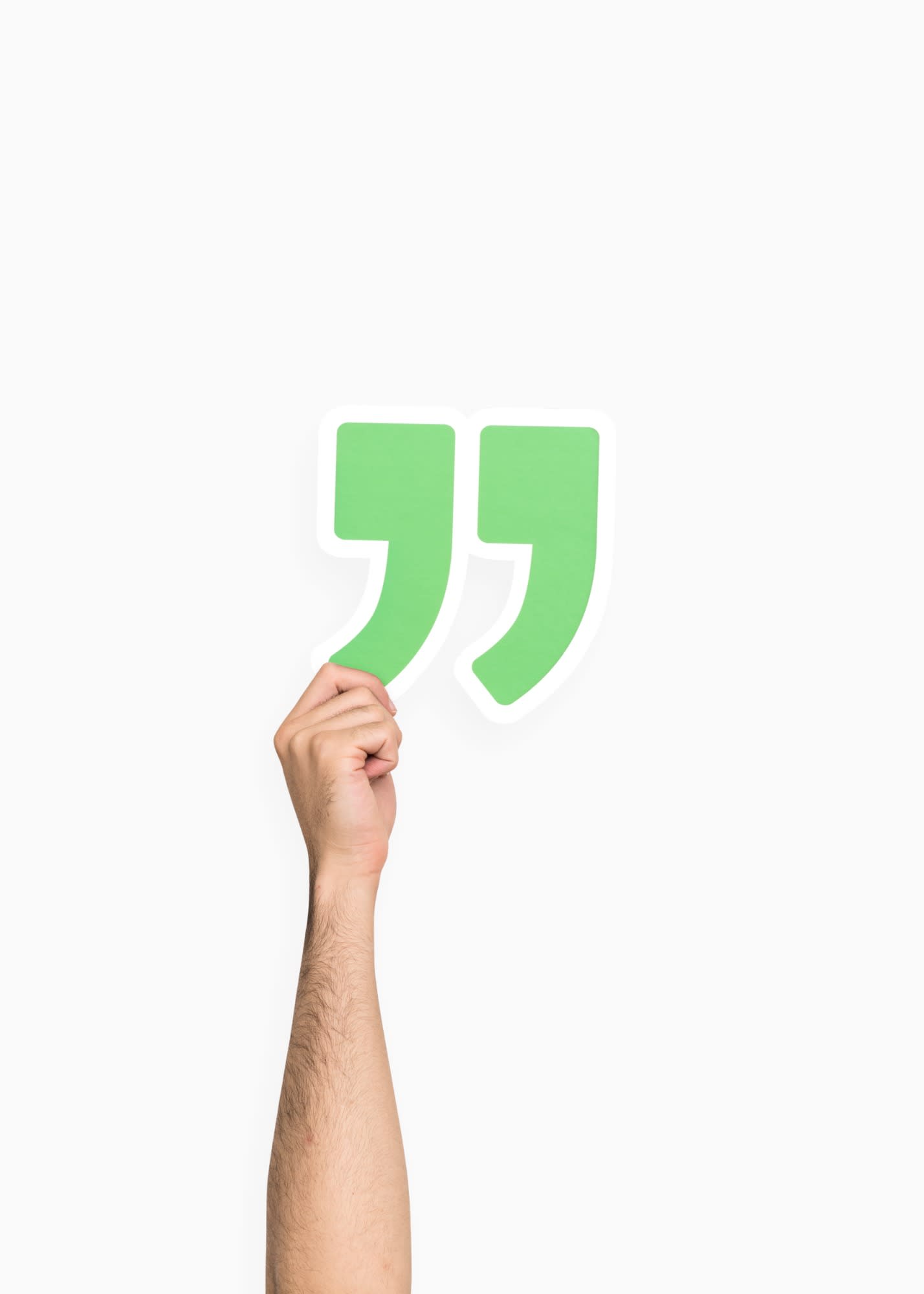 A vertical view of an arm and hand holding up a green quote mark sign.