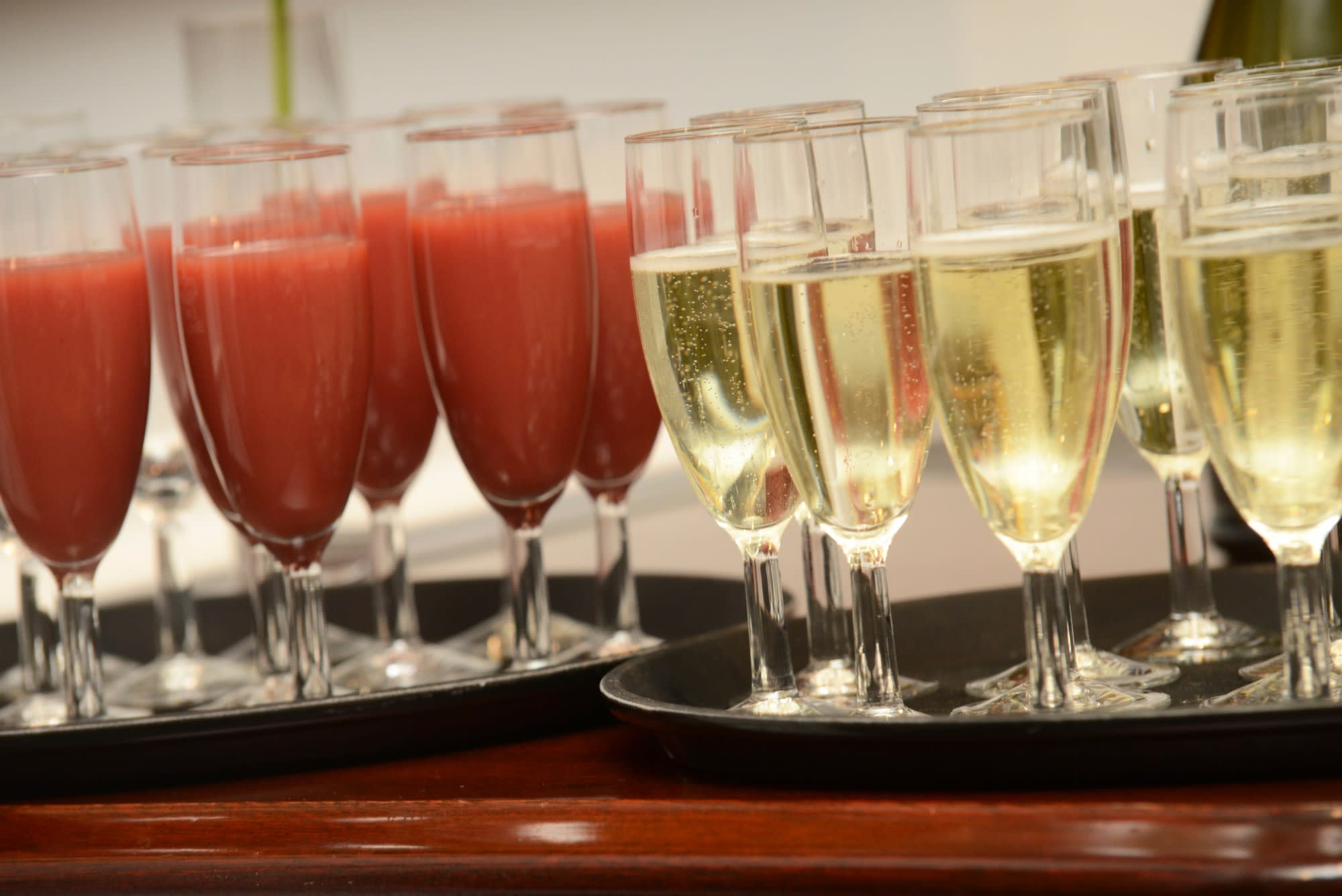 Trays filled with tall glasses, full of champagne and a pink-coloured drink