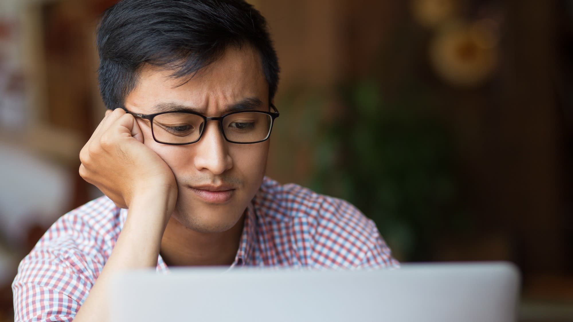 bored-young-asian-male-student-sitting-laptop