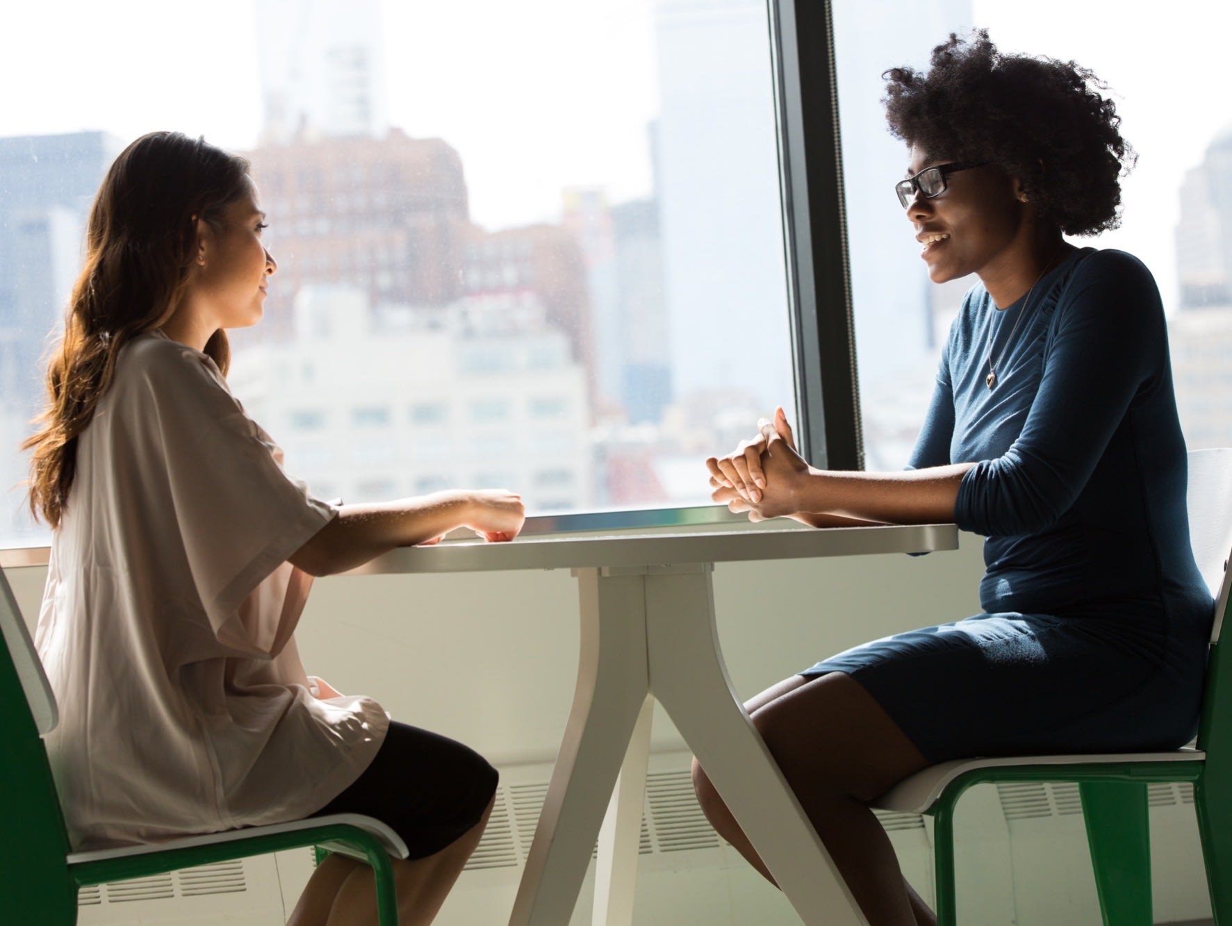 two women sitting at table talking