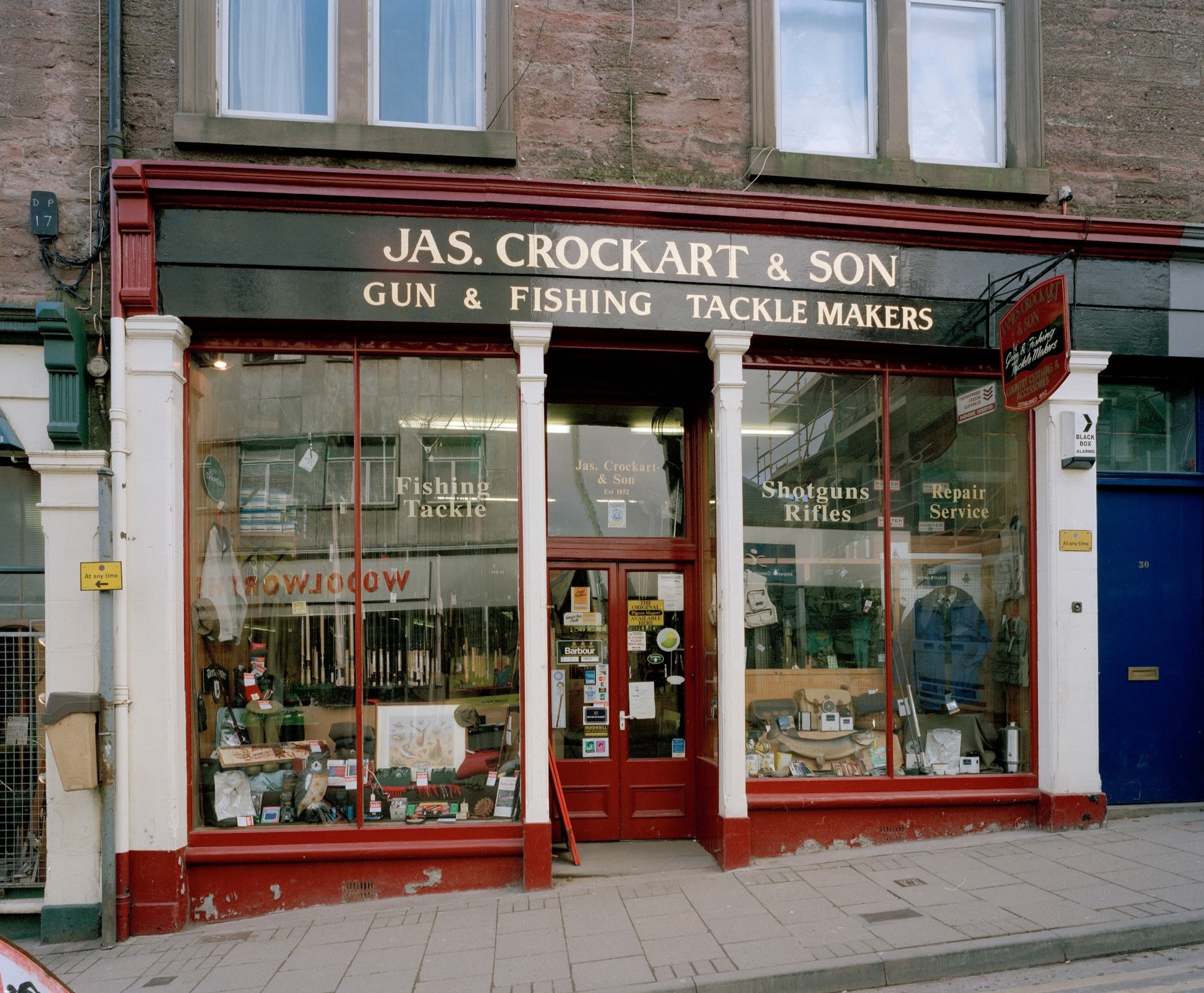 A traditional shop with full length windows packed with products and displays