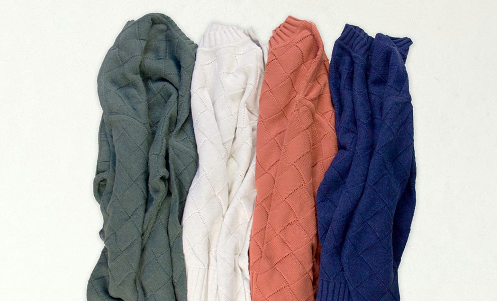 Flatlay image of four basket weave sweaters in green, white, salmon, and navy colorways.